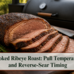 Sliced smoked ribeye roast with a dark seared crust on a carving board beside a smoker